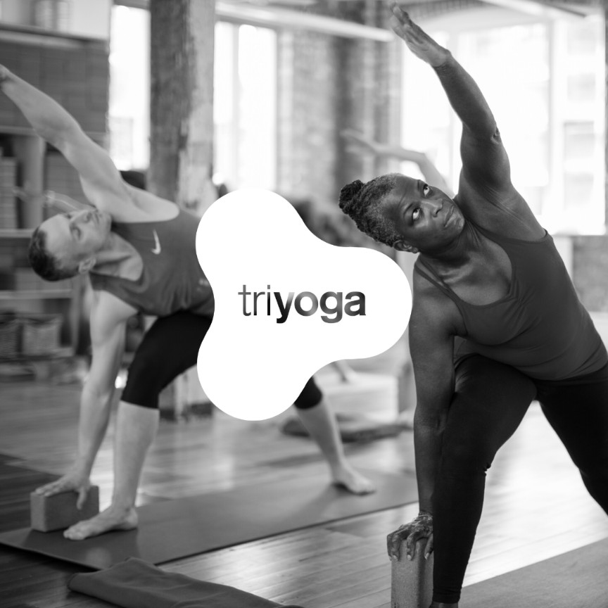 Triyoga students practicing extended side angle pose with blocks in a supportive, inclusive studio environment focused on mindful movement and alignment.