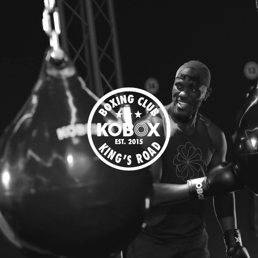 KOBOX client training with a heavy bag during a high-energy boxing class, combining power, cardio, and nightclub-style atmosphere.