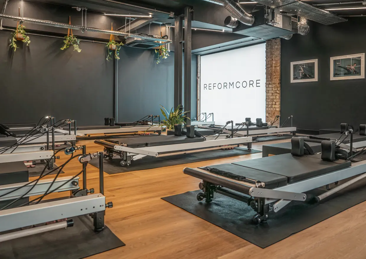 Reformcore studio interior featuring state-of-the-art Reformer machines, clean architectural design, and a boutique Pilates environment designed for strength and precision.